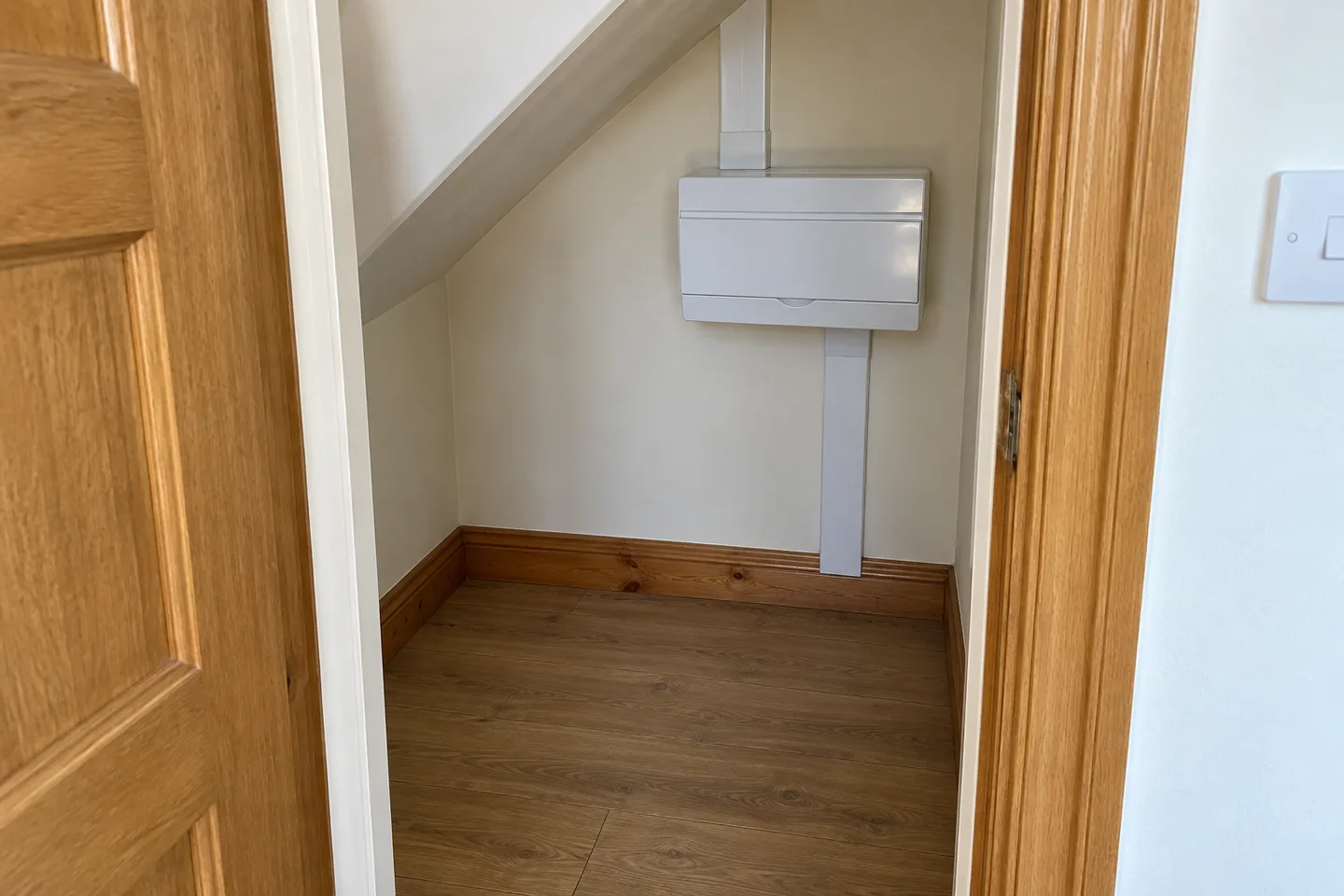 Cleared under-stairs cupboard with a closed consumer unit and unobstructed access