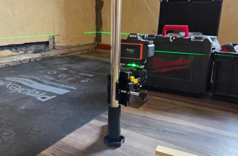 Floor protection laid down and a laser level set up before electrical work begins